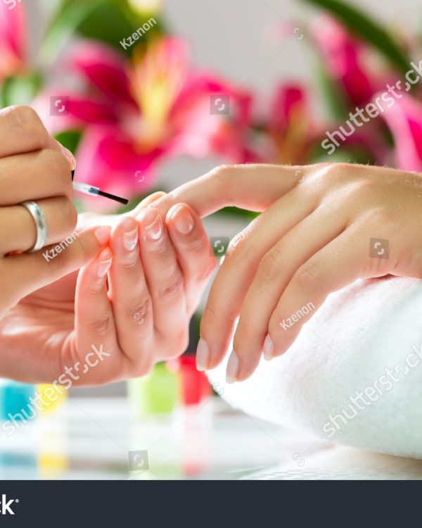 stock-photo-woman-in-a-nail-salon-receiving-a-manicure-by-a-beautician-113068372